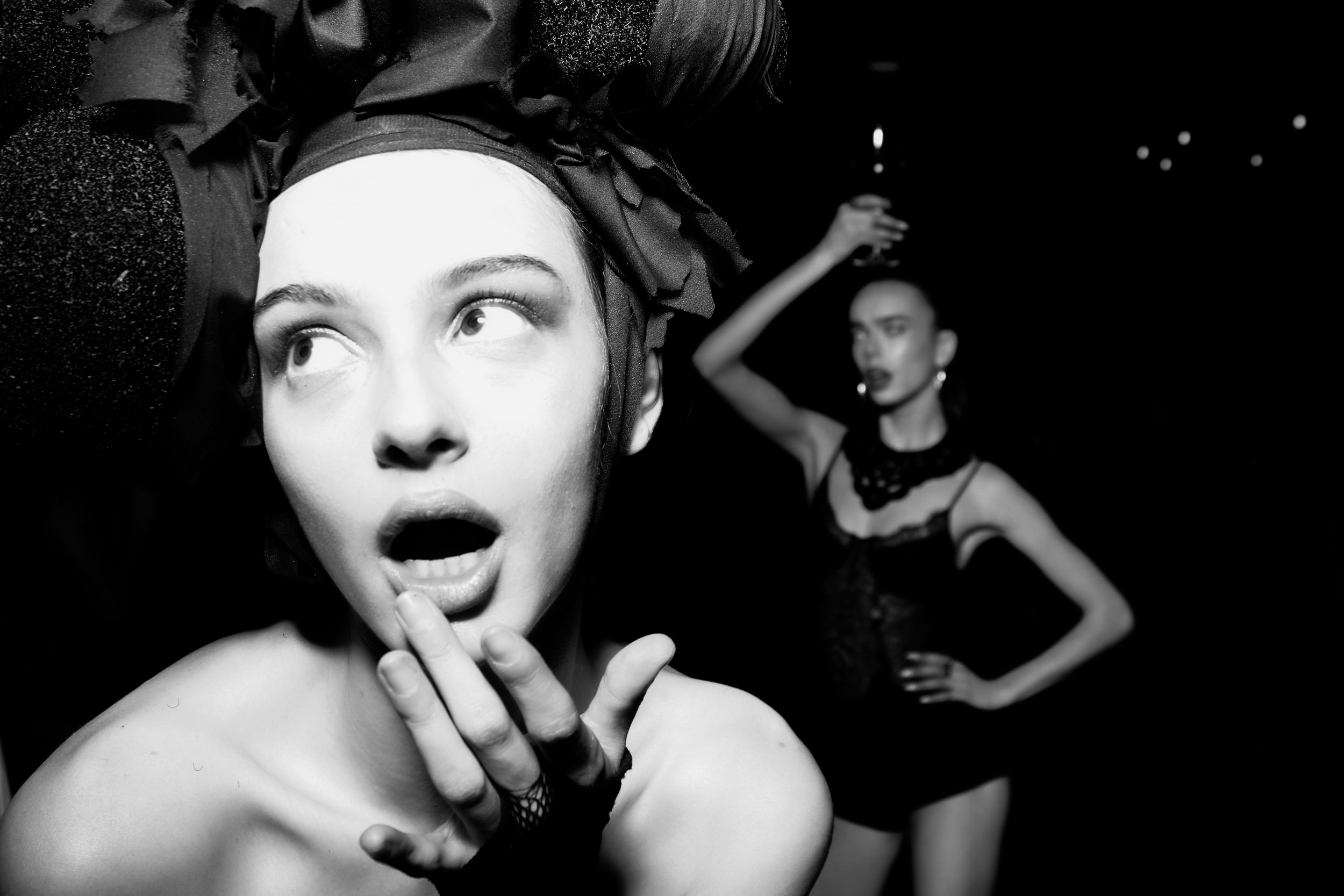 A dramatic black and white party scene with people in dark clothing at a nightclub.