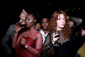 People dancing and socializing at a dimly lit party or nightclub with red lighting effects.