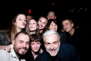 A group of people smiling and posing together for a casual photo in dim lighting.