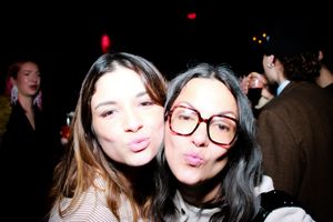 Group of friends having fun and making silly faces while taking selfies at a dark party venue.