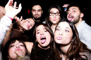 A group of friends make silly faces and poses together while taking a fun photo booth style picture.