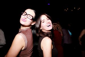 Two people laughing together at a dimly lit party or social gathering.