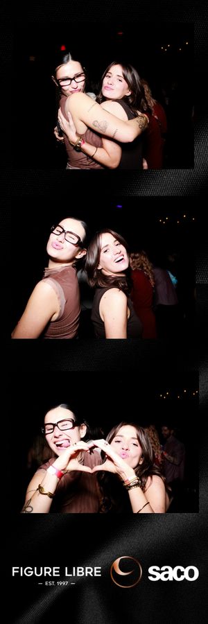 Two friends pose playfully together in a dark nightclub photo booth with Figure Libre Saco branding.