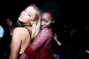 People dancing and socializing at a dark nightclub with red lighting effects.