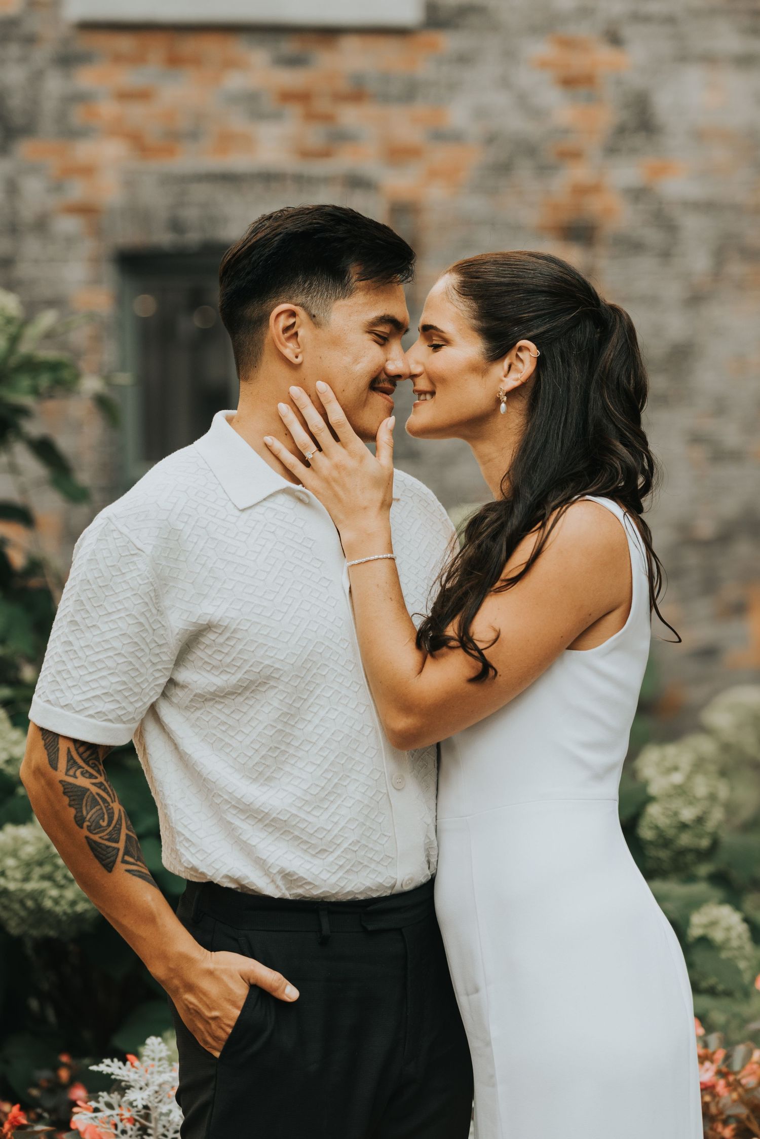 A romantic couple shares intimate moments against a brick wall backdrop in a series of candid photographs.