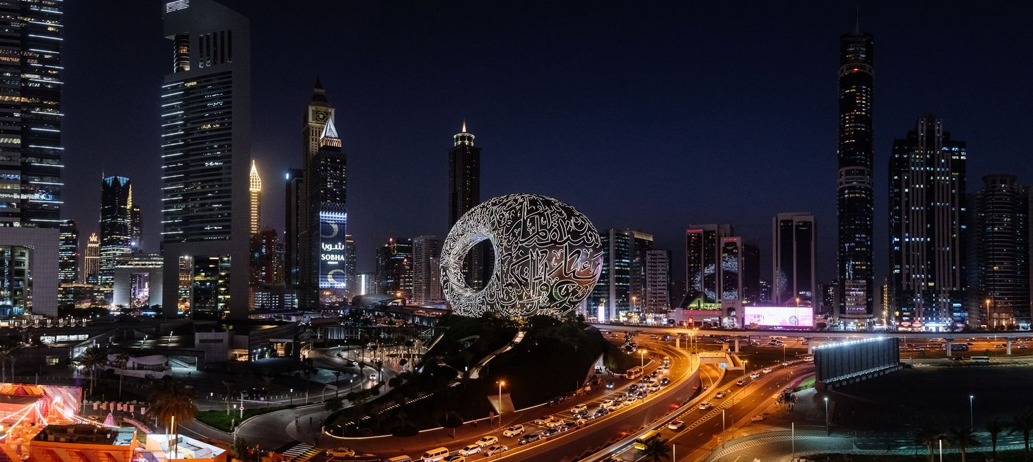 Night skyline of Dubai with illuminated skyscrapers and highways.