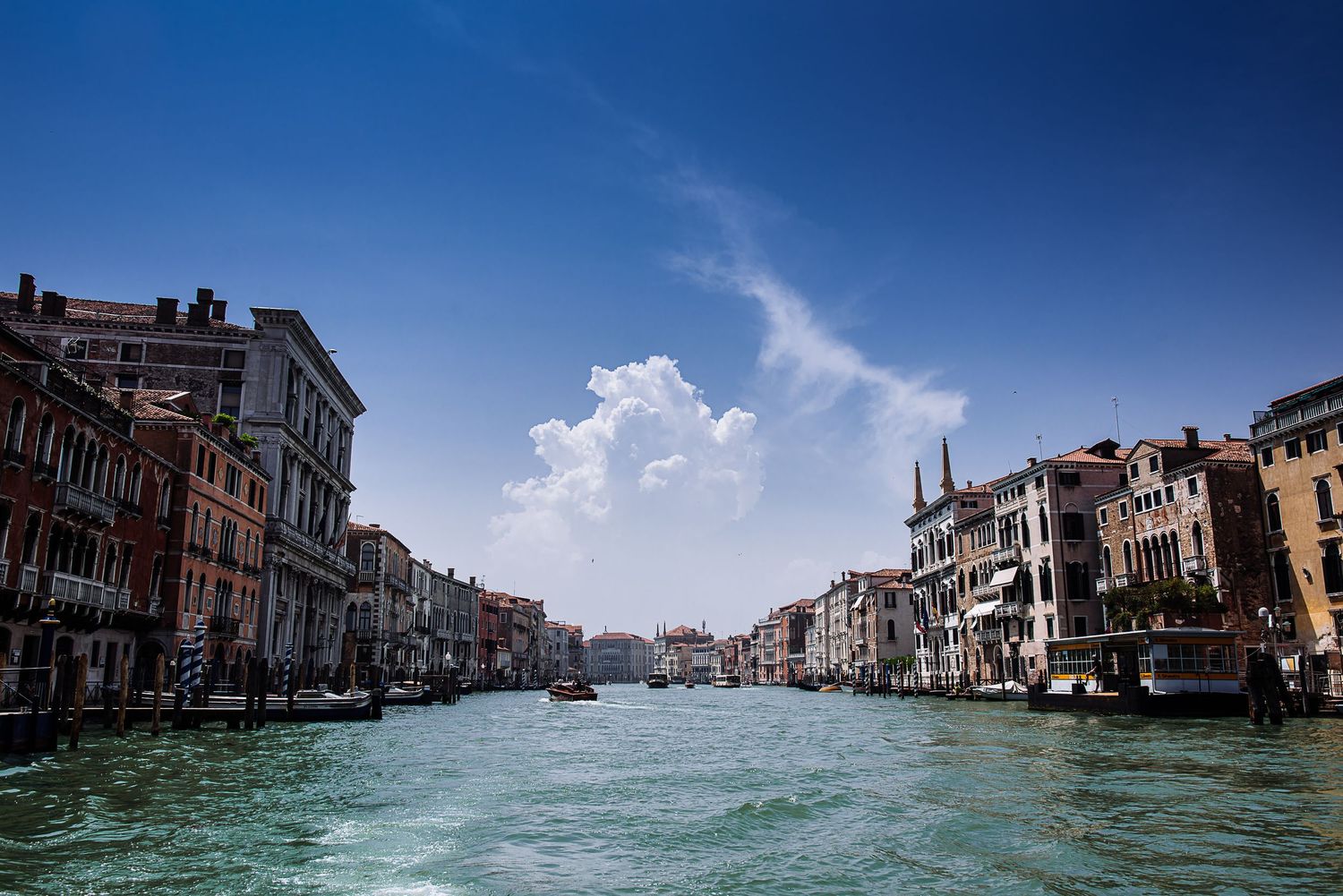 Panoramic view of Venice's Grand Canal with historic buildings and blue water under clear skies.