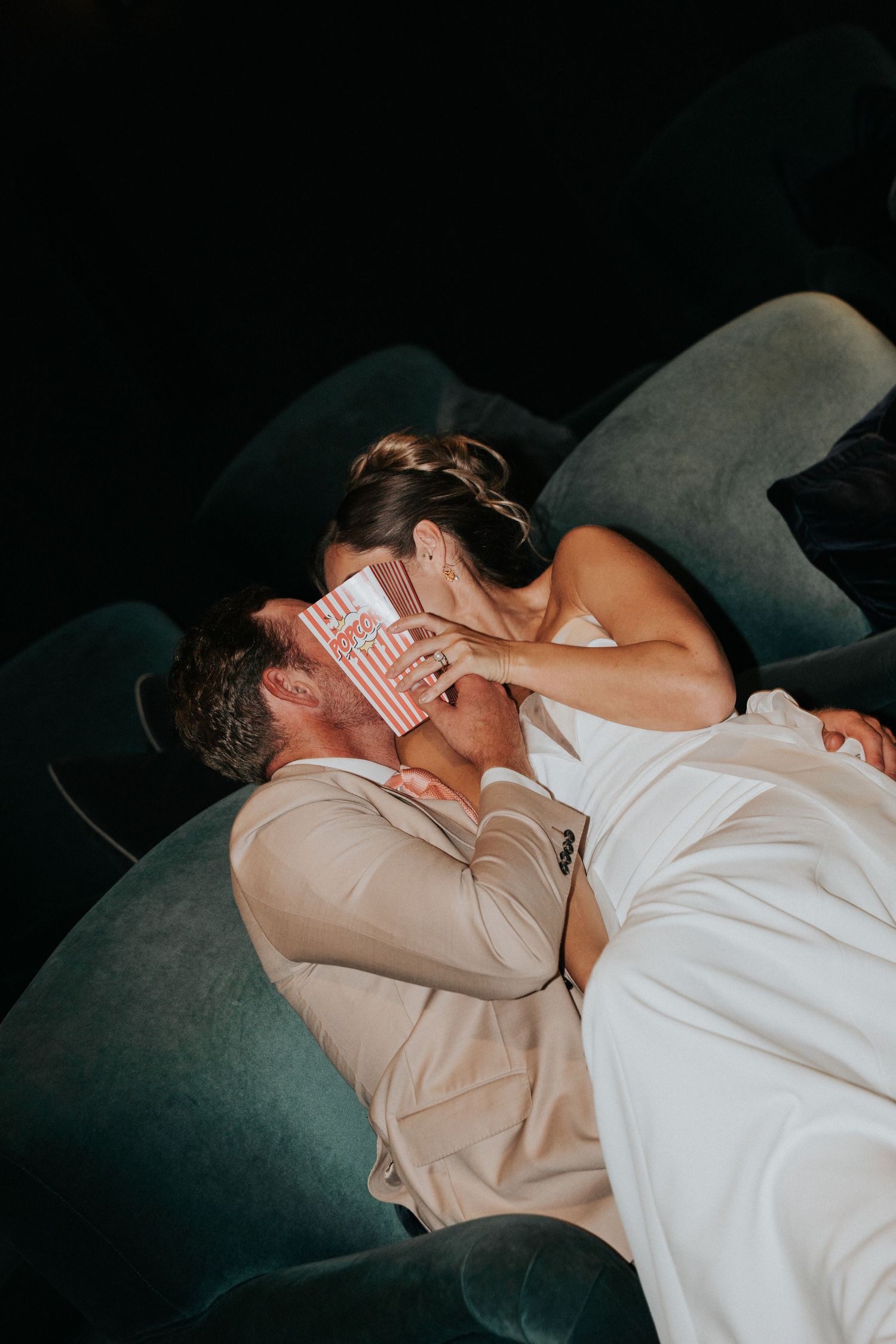 Close, intimate portrait of a bride and groom relaxing together in the cinema at Gara Rock Hotel during a styled wedding shoot, highlighting