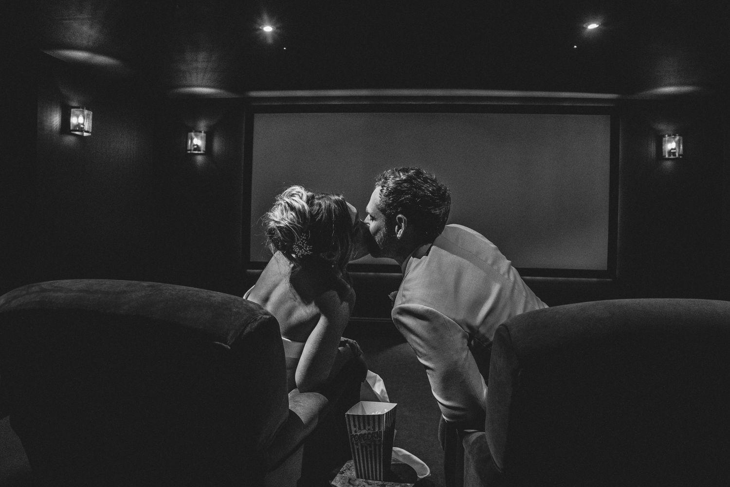Black and white editorial portrait of a bride and groom kissing in the private cinema at Gara Rock Hotel.