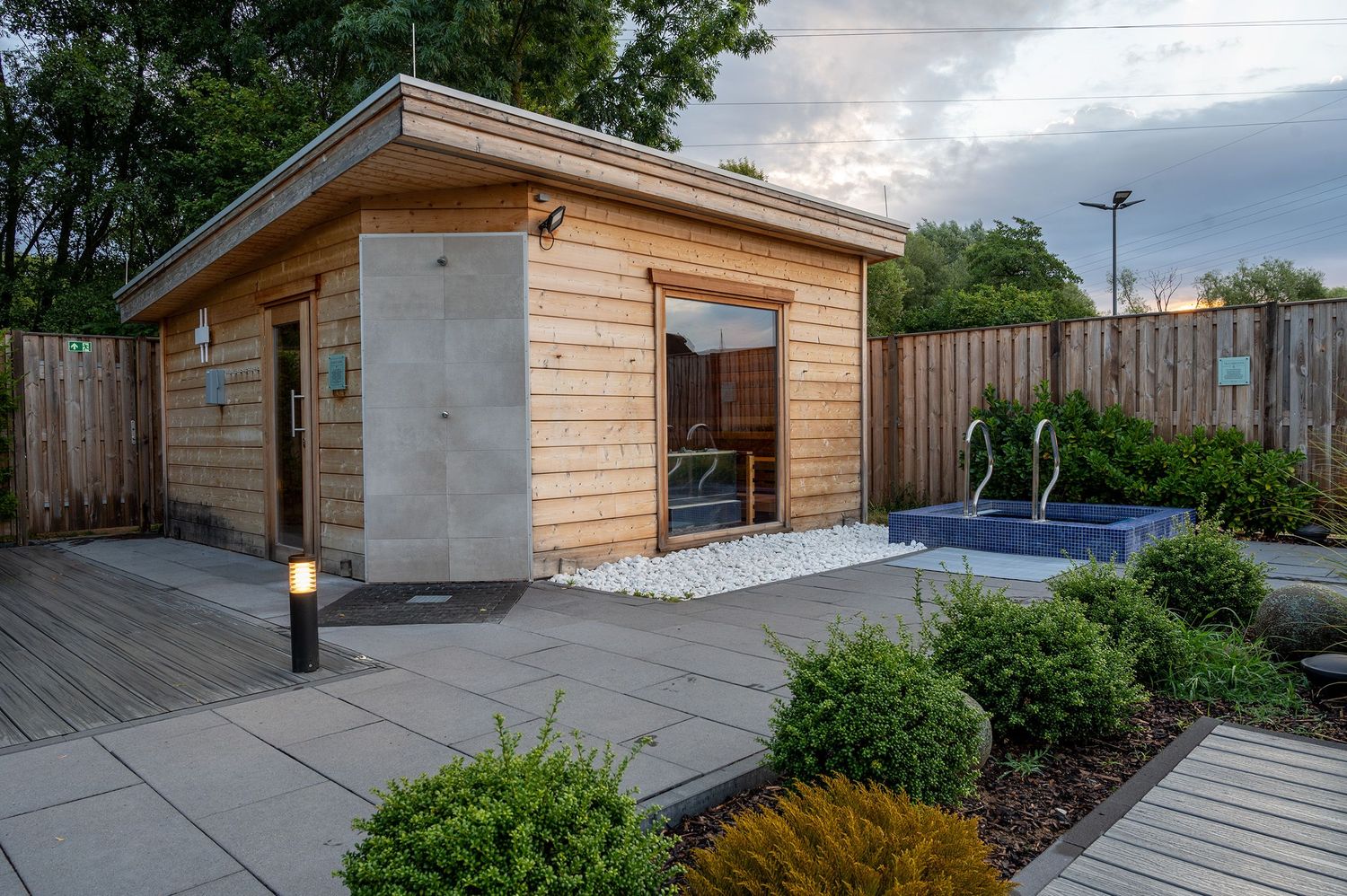 Modern backyard design featuring concrete pavers, wood paneling, and contemporary landscaping elements.