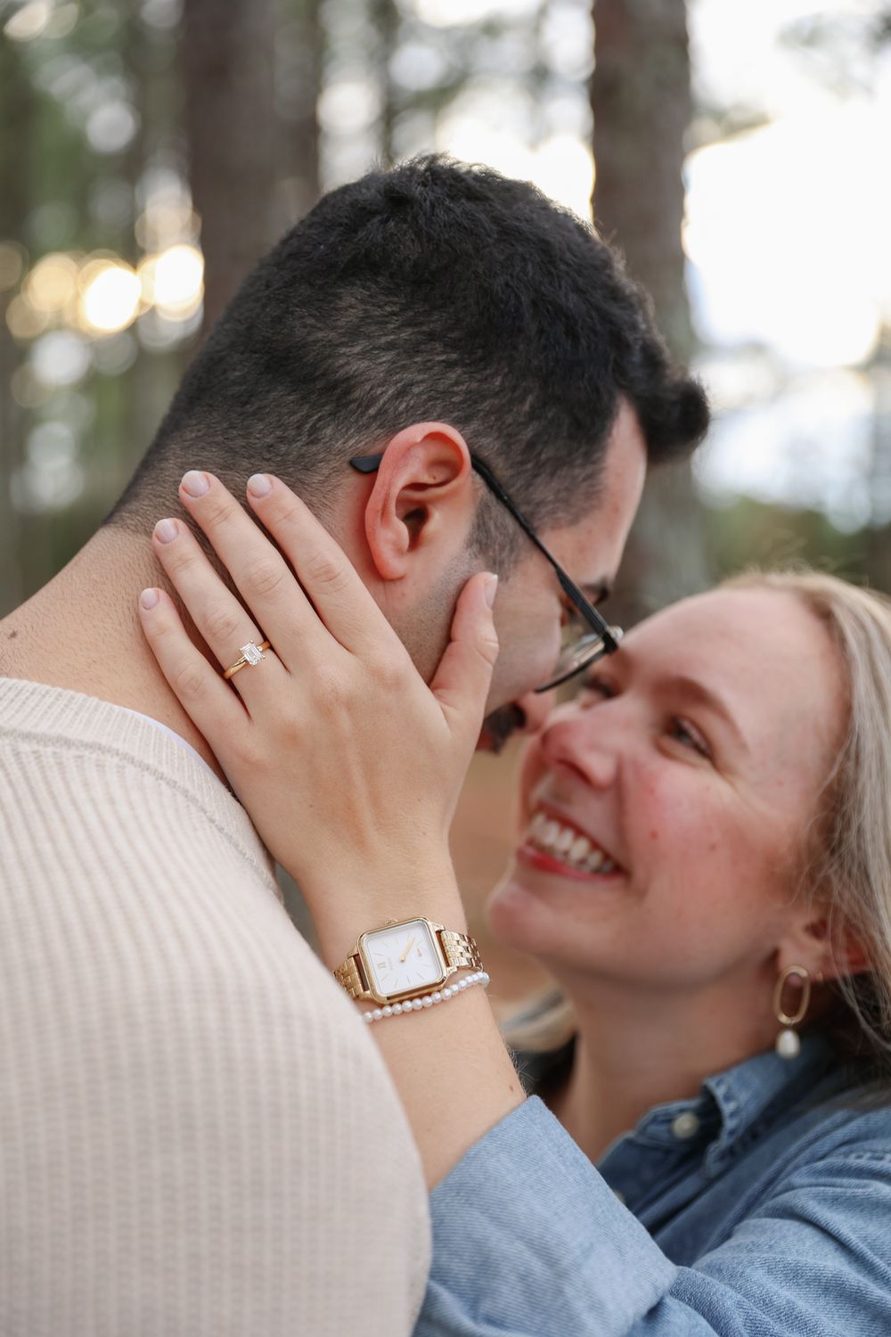 Close-up of an intimate moment between a couple sharing laughter and tender touches in a forest setting.