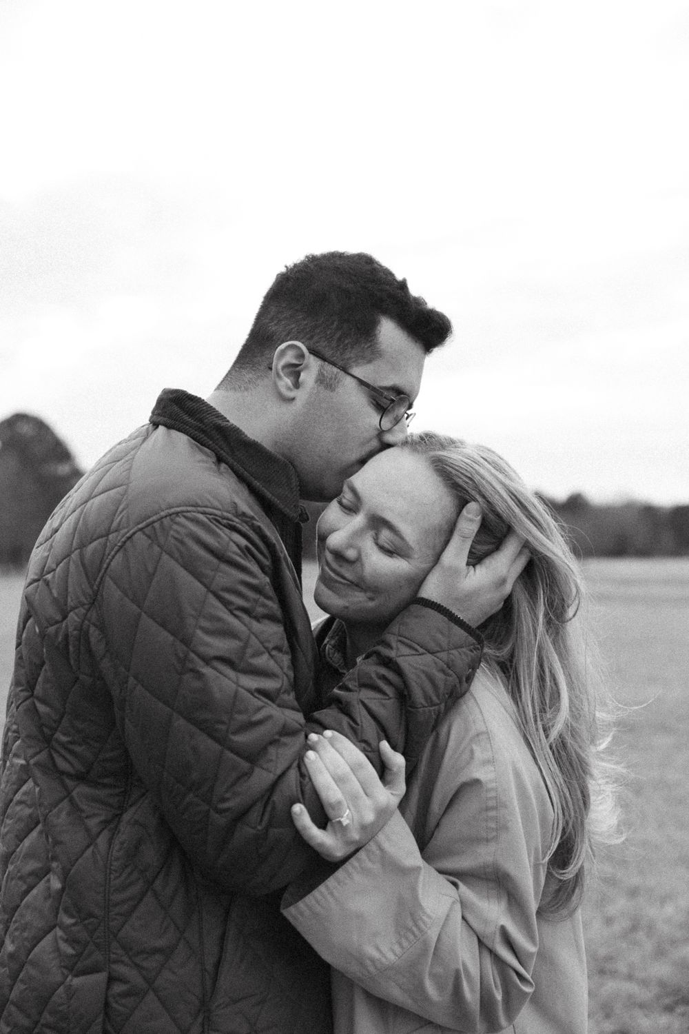 A romantic black and white photo of a couple sharing an intimate moment outdoors in casual winter attire.