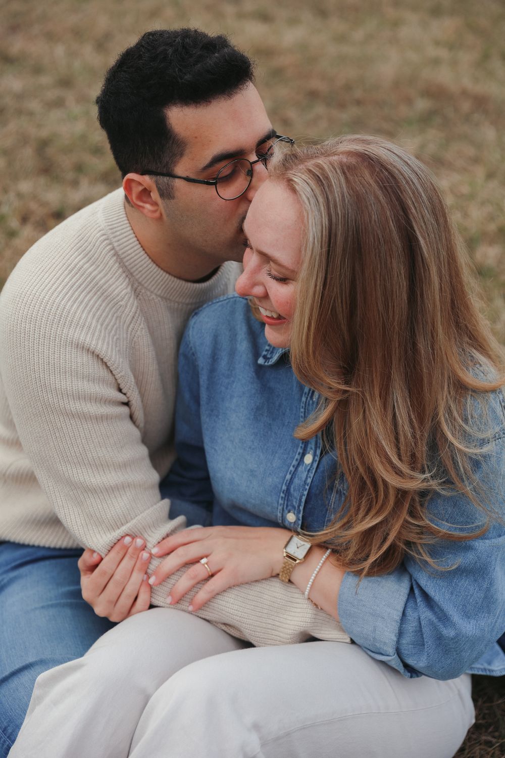 A romantic couple in casual attire sharing tender moments while sitting together outdoors.