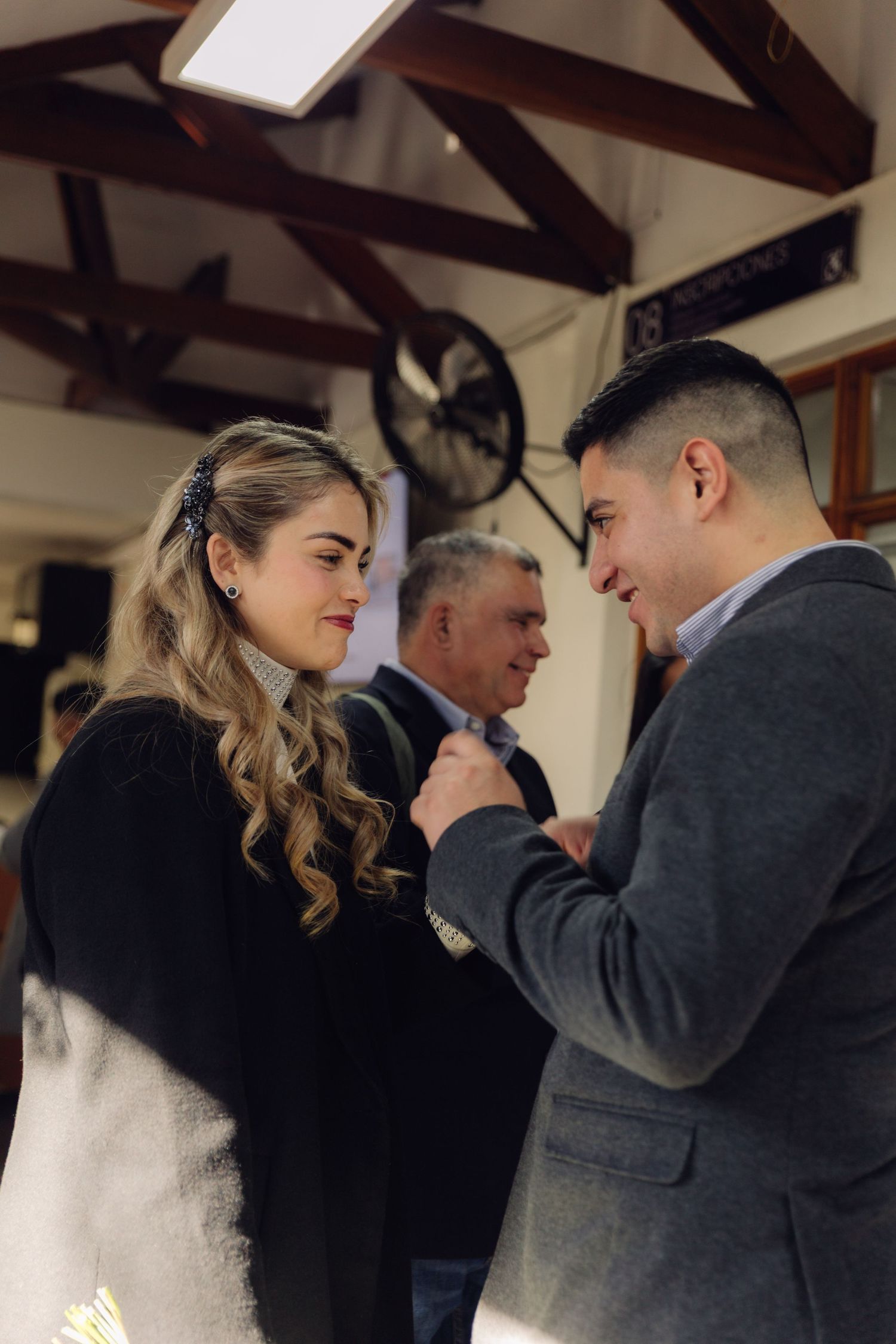 Man holding woman's hand tenderly during a formal indoor ceremony event.