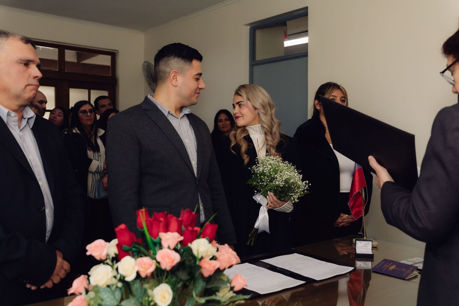 Officiant presenting documents to couple during civil wedding ceremony with guests.