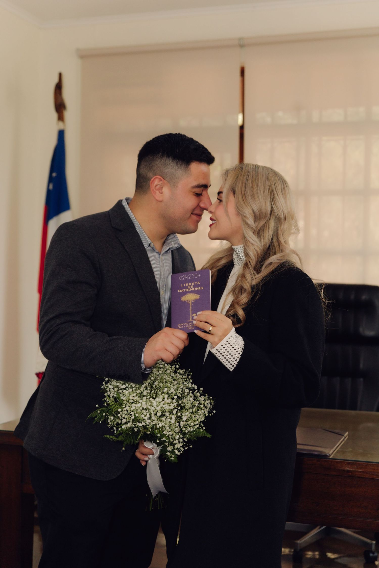 Newlywed couple shares a romantic nose-to-nose moment holding marriage certificate.