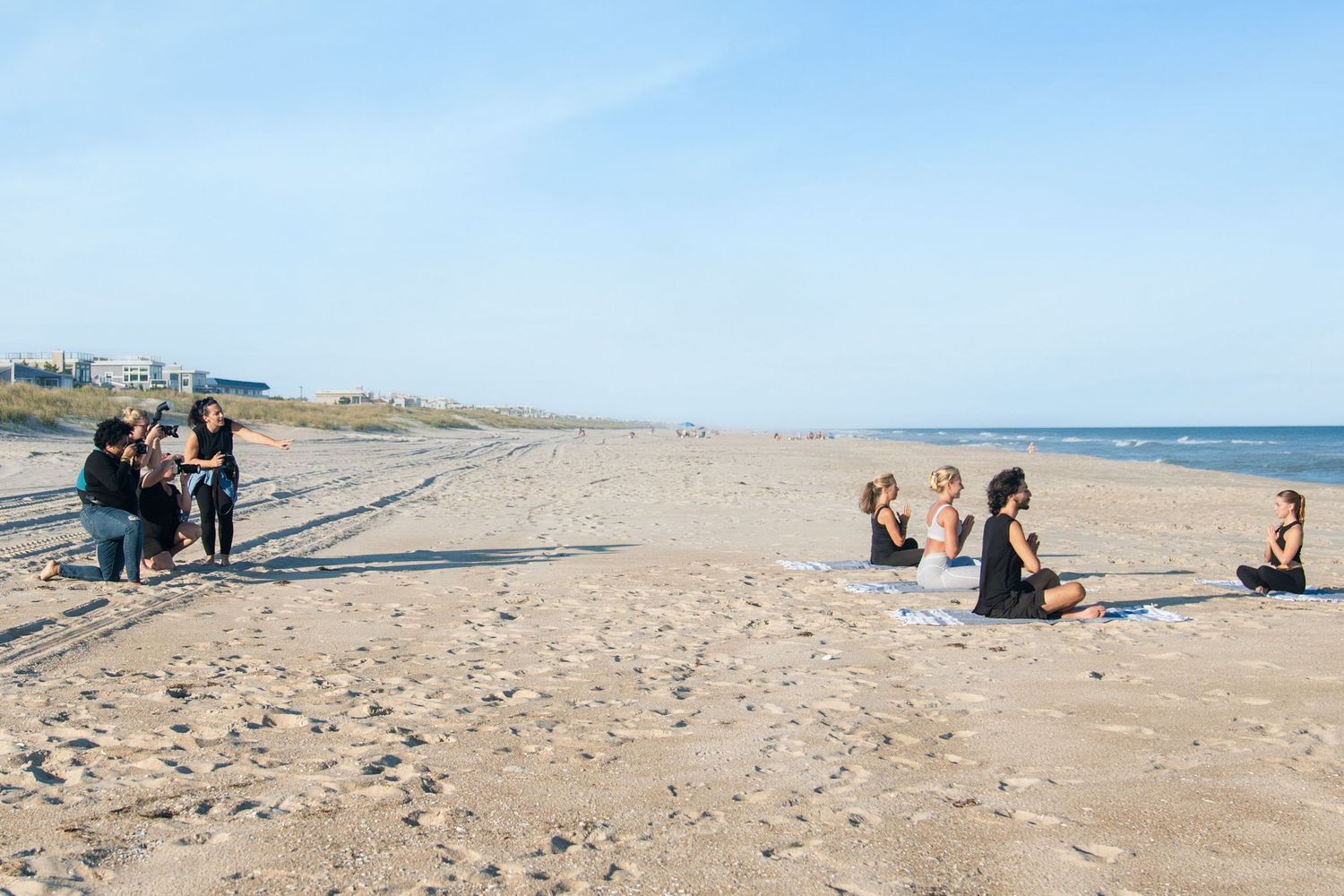 Wide angle view of sandy beach with scattered groups of people on a sunny day.