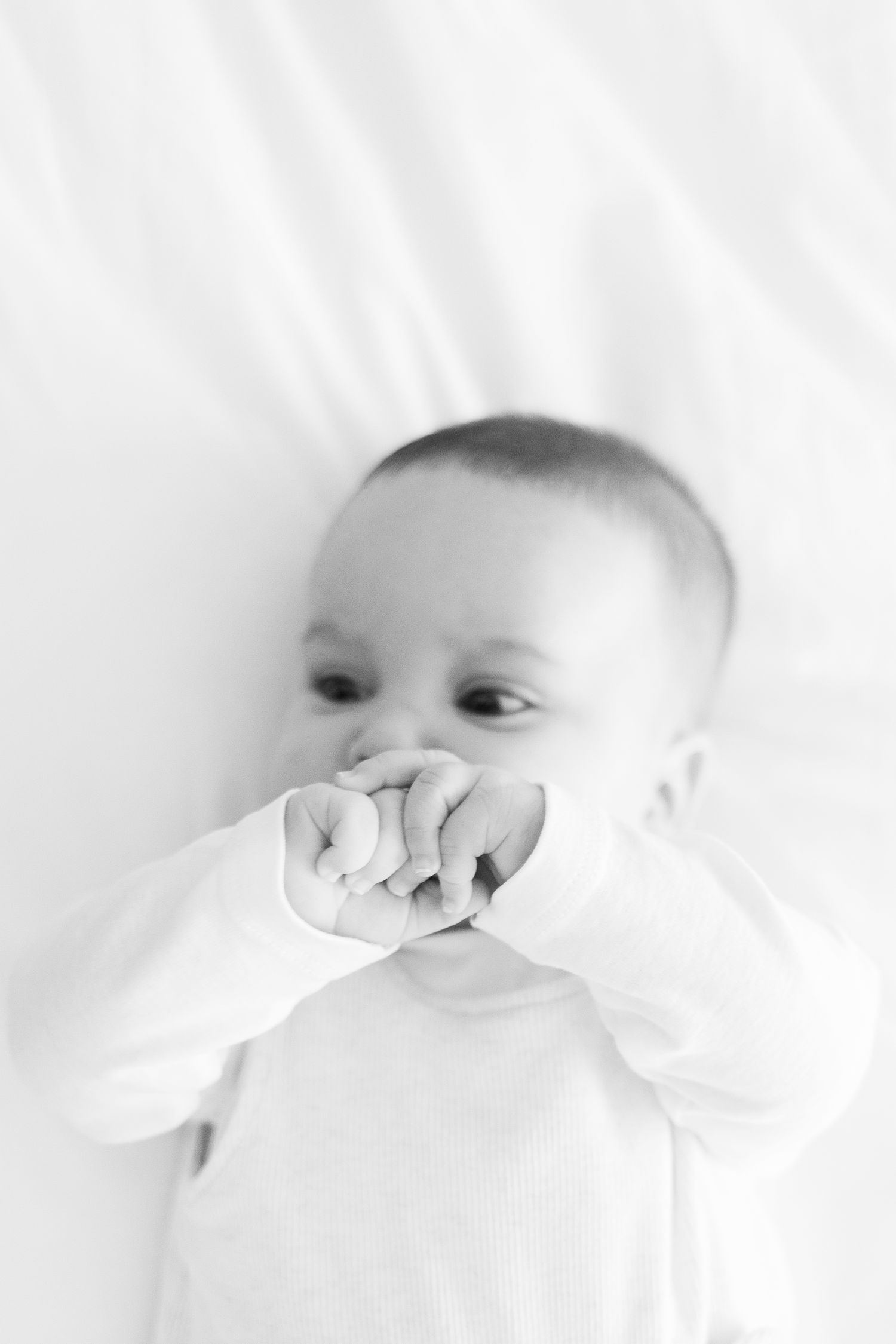 A series of black and white close-up photographs showing a baby's facial expressions against a white background.