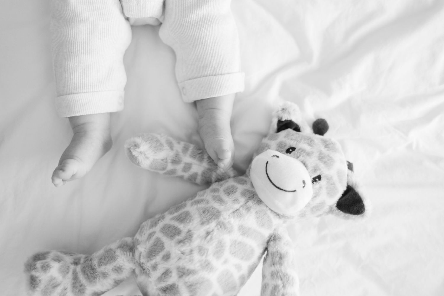 Black and white photo collage of an infant lying on white bedding with various poses and expressions.