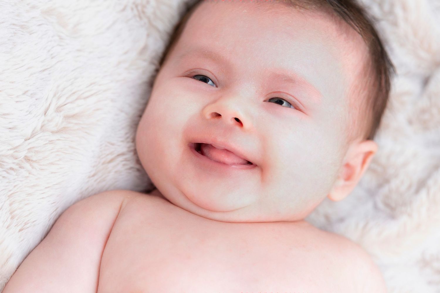 Happy baby lying on white blanket showing joyful expressions in a series of connected photos.