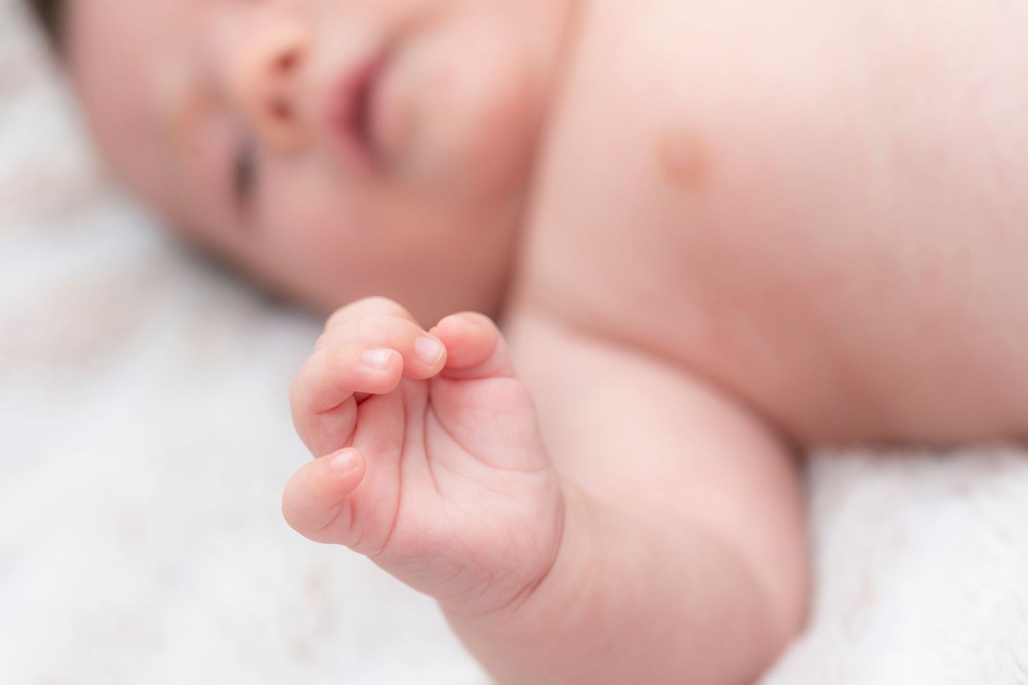 Close-up view of a tiny baby's delicate fingers and toes against a soft white background.