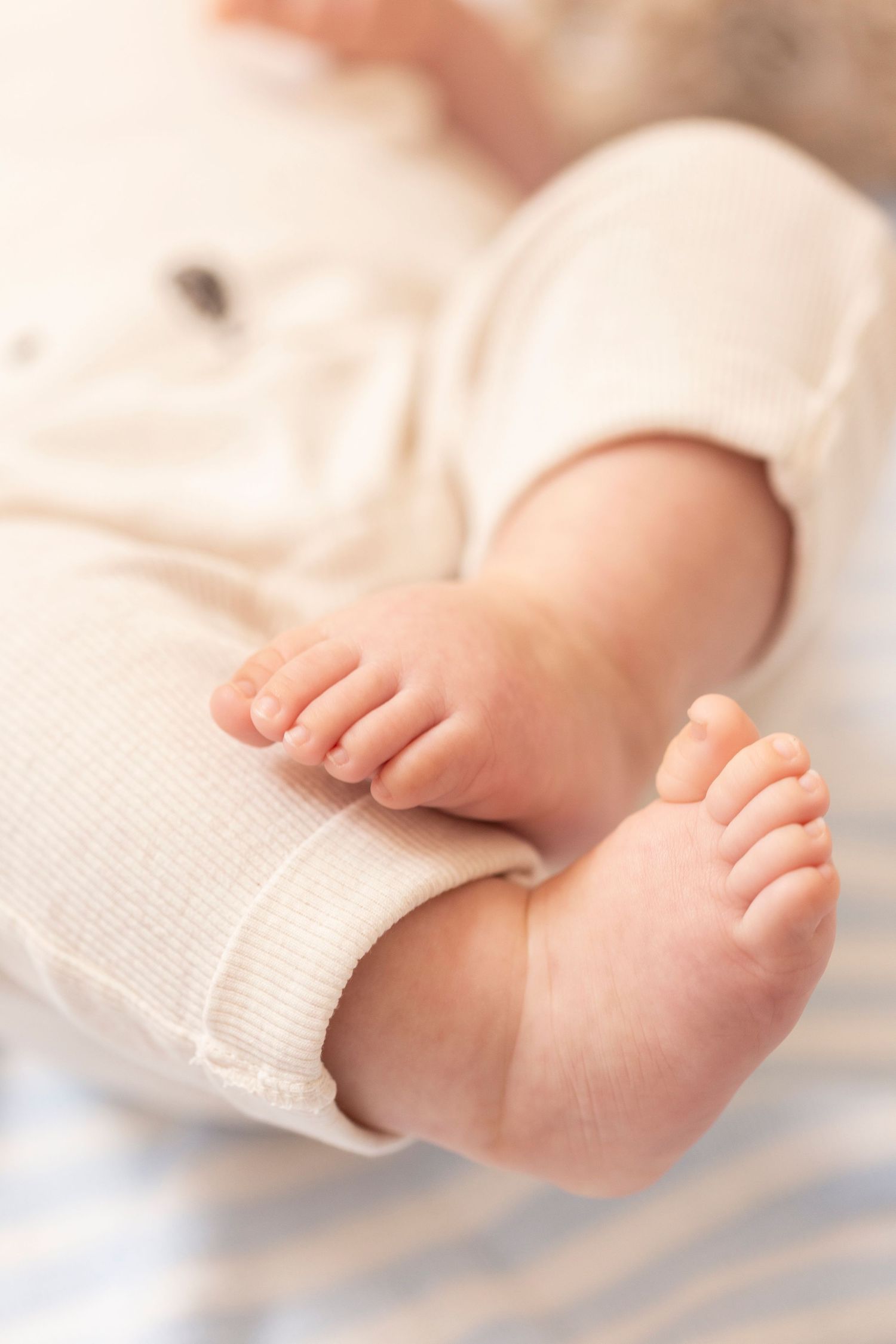 Delicate bare feet of a sleeping infant resting on white textured fabric.