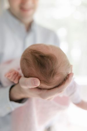 A series of photos showing a sleeping baby being gently cradled in someone's hands against a soft white background. Hartford Newborn Photogr