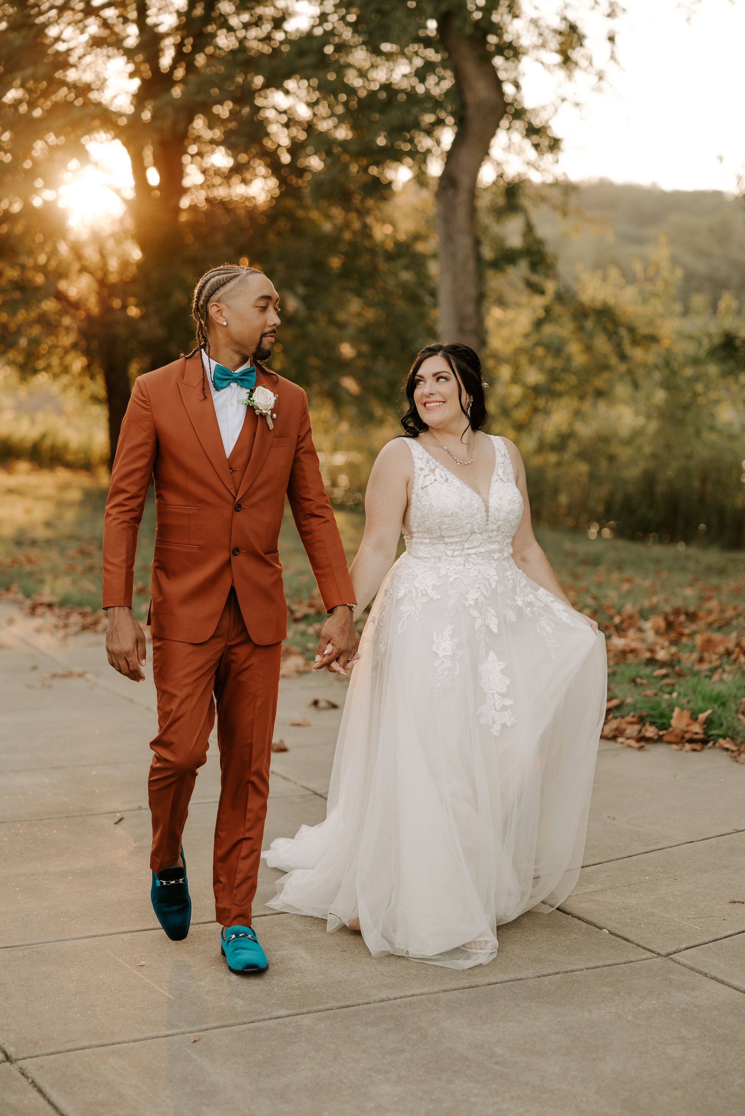 Wedding couple walking together, groom in striking rust-colored suit with turquoise shoes.