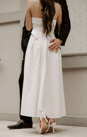 Close-up of formal attire and white heels during an intimate dance moment.