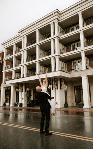 A couple dances in front of a columned building with dramatic dips and spins.