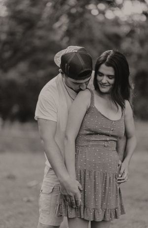 A tender black and white portrait of a couple sharing a sweet moment outdoors.