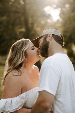 A romantic couple shares tender moments in soft golden sunlight outdoors.