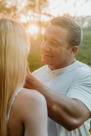 A tender moment between a couple during golden hour with sunlight streaming through trees.