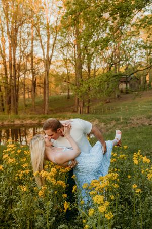 Romantic couple embracing in a field of yellow wildflowers at sunset.