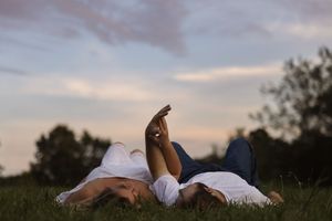 Silhouetted couple lying in the back of a pickup truck against a dusky sky.