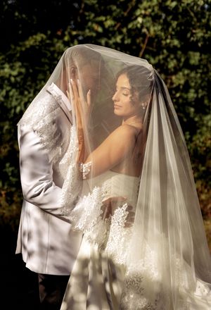 Artistic bridal portrait series showing flowing white veil and lace dress details in natural light.