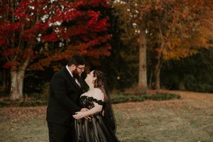 A romantic autumn wedding photo with vibrant red maple trees in the background.