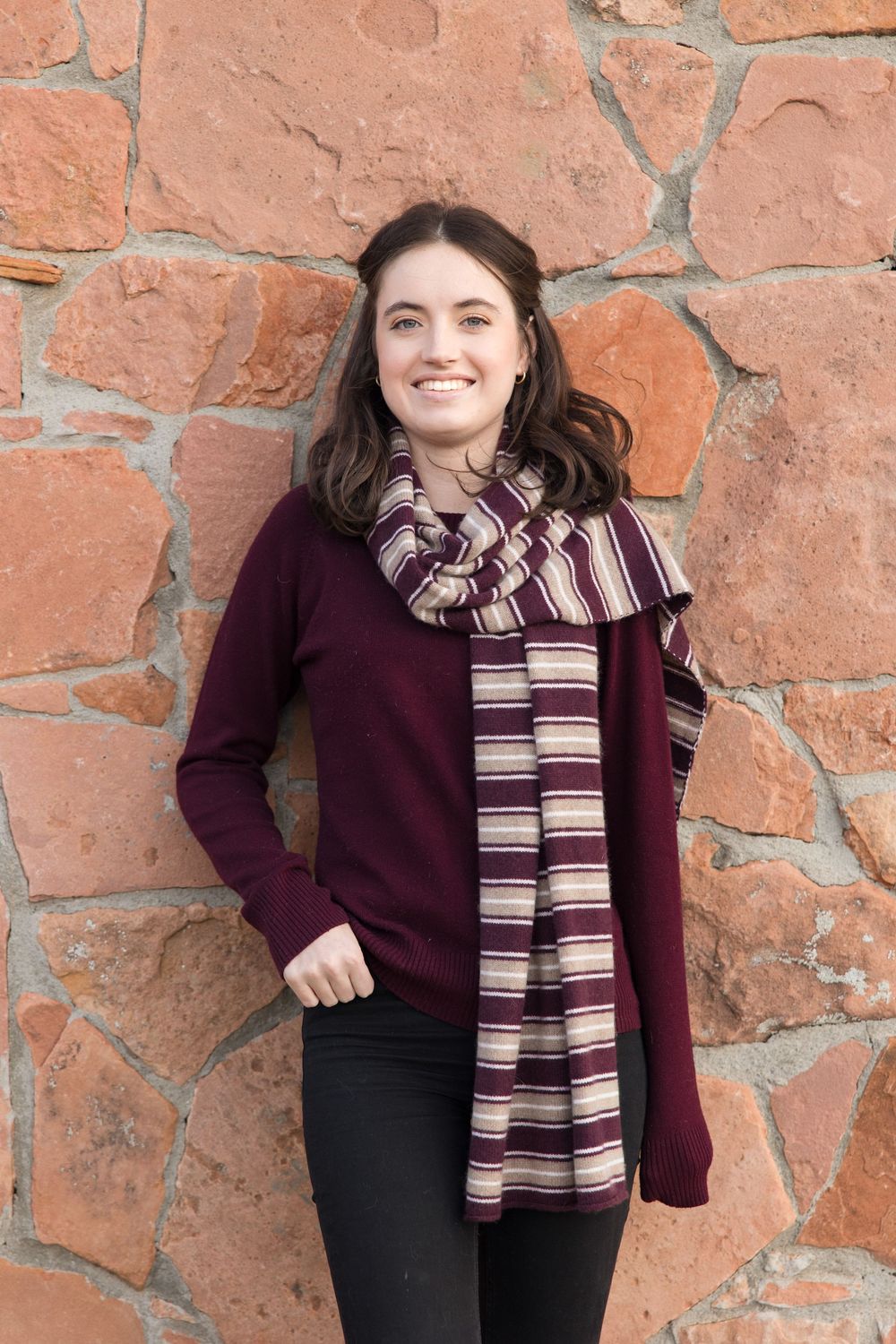 Woman in burgundy sweater and striped scarf poses against rustic orange stone wall in multiple candid shots.