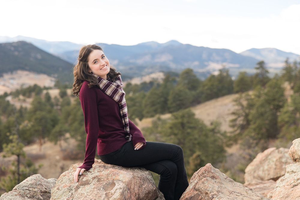 Scenic mountain engagement photo session with couple enjoying views on rocky overlook at sunset.