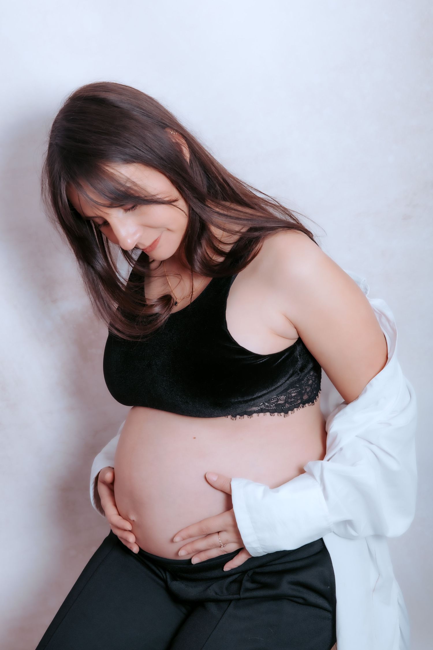 A woman in black and white clothing holds her pregnant belly in a series of maternity photoshoot poses.