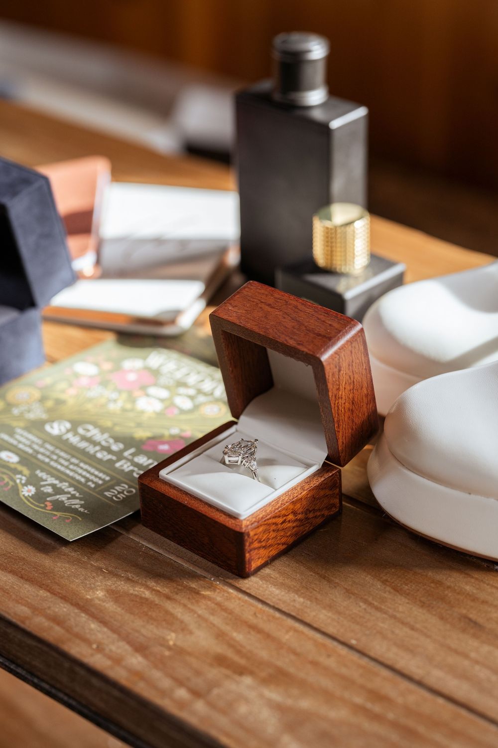 Small wooden boxes and wedding invitations arranged on rustic wooden table surface.