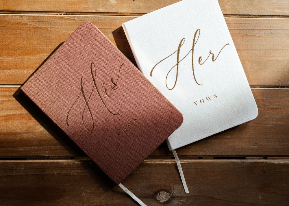 Wedding vows and stationery displayed on rustic wooden table with elegant calligraphy.