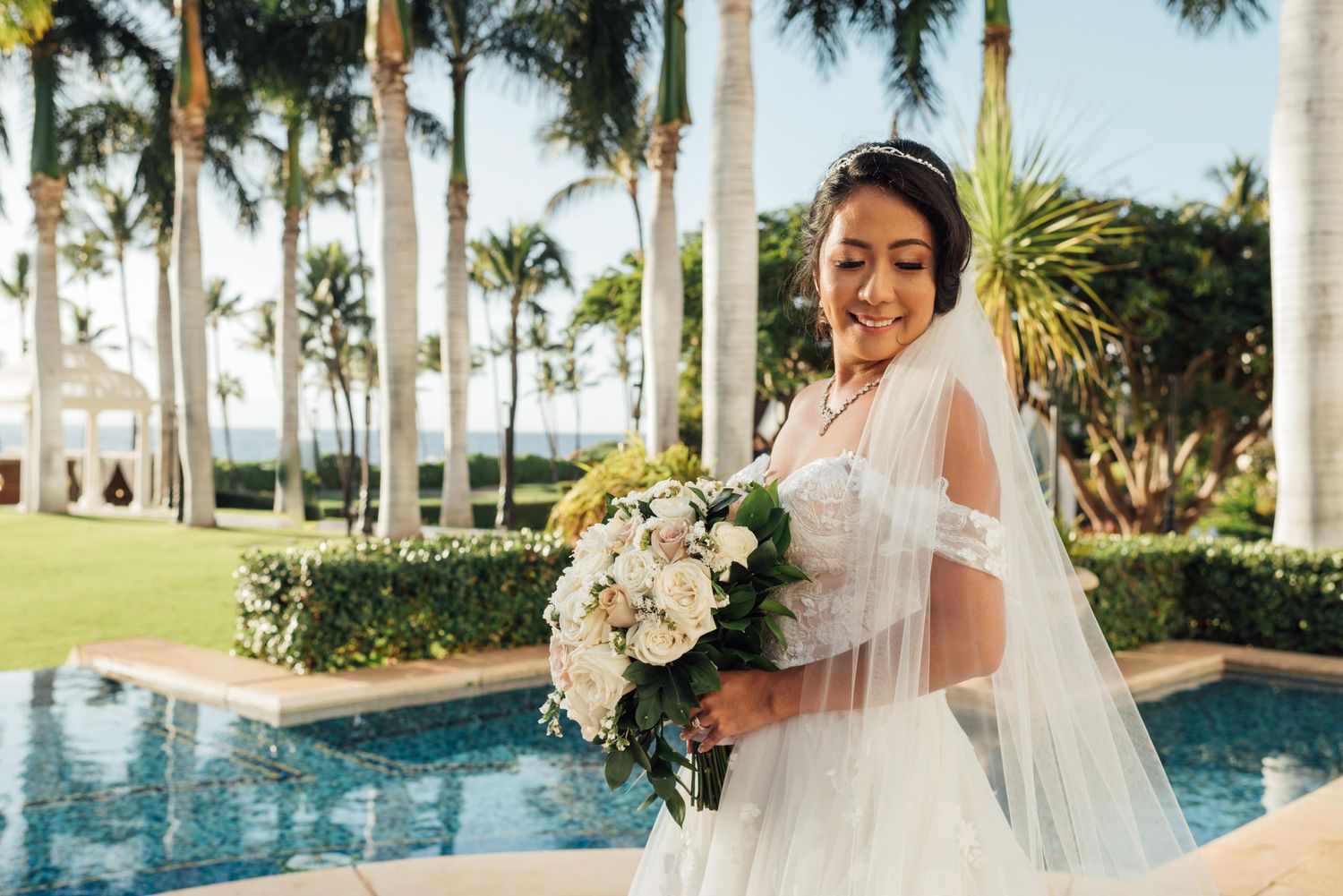 Elegant poolside wedding venue with palm trees and tropical landscaping.