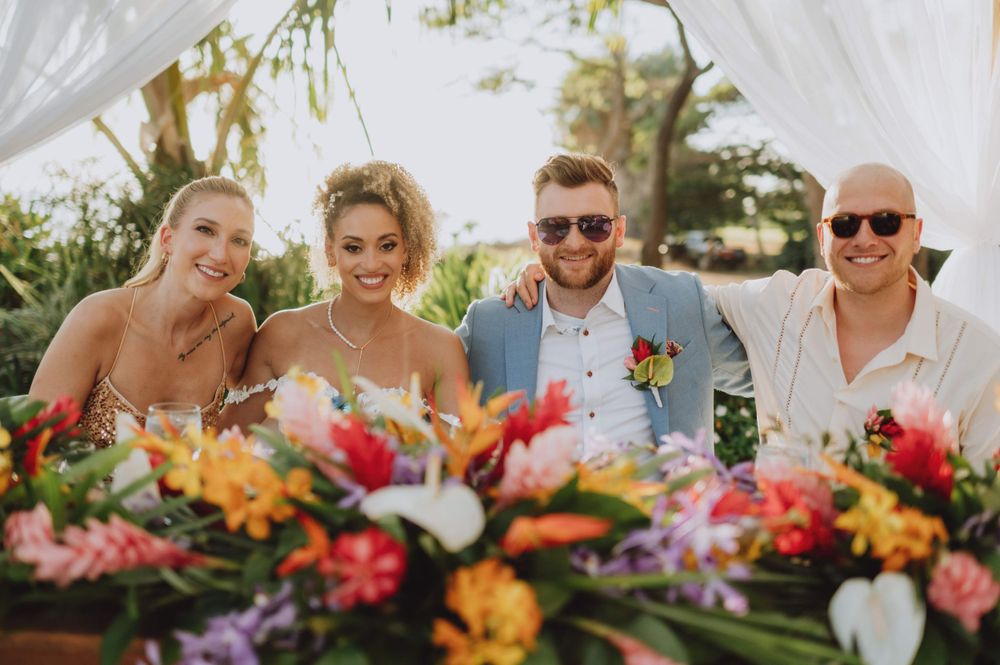 Colorful tropical flower arrangements decorating an outdoor wedding reception table.