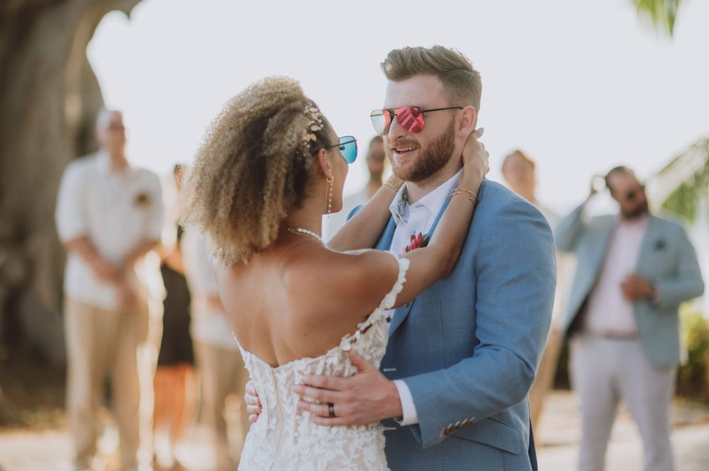 Outdoor wedding ceremony setup with tropical floral arrangements and white decor.