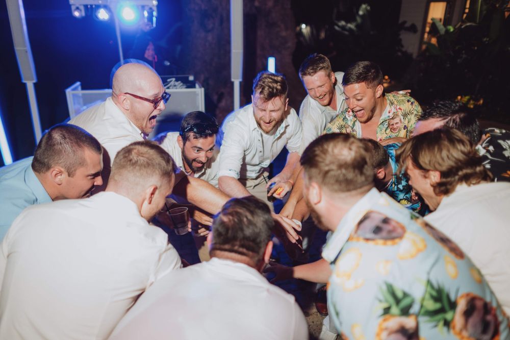 Wedding guests dance and celebrate enthusiastically at an indoor reception.