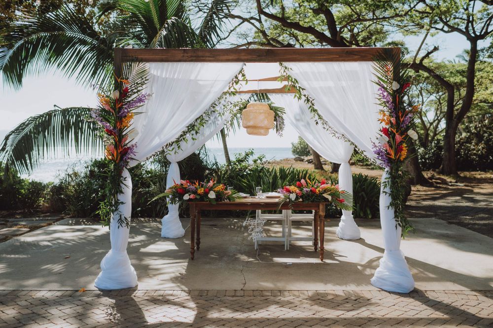 Tropical beach wedding ceremony setup with palm trees and white decor.
