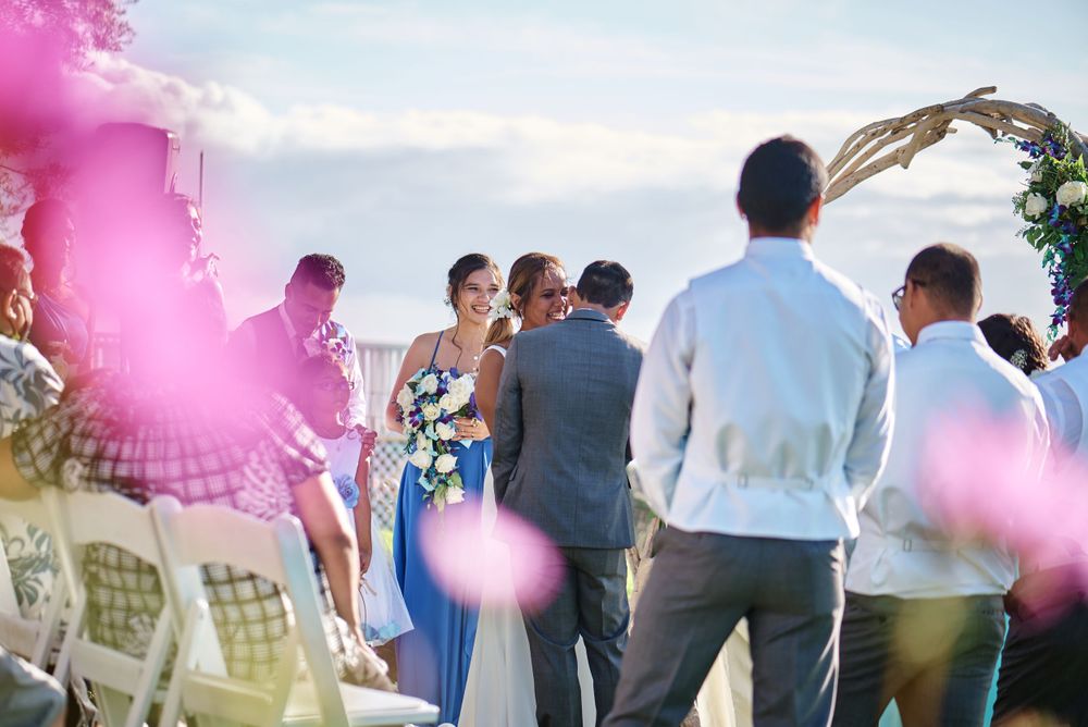 Pink smoke fills the air during an outdoor celebration as guests gather on a grassy hillside.