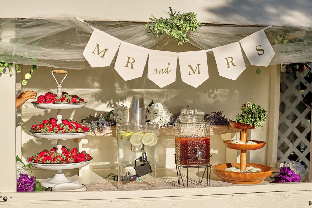 Wedding reception dessert table decorated with white banners, flowers, and fresh strawberries.