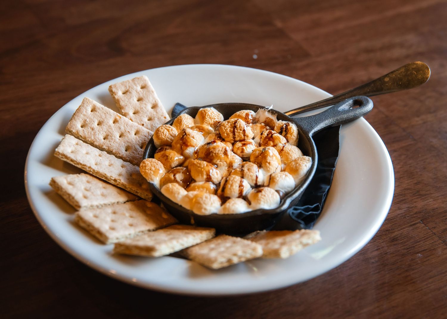 Cast iron skillet filled with creamy buffalo chicken dip served with crispy crackers on a white plate.